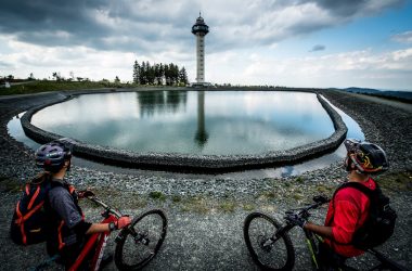 Zwei Mountainbiker am Hochspeicherbecken mit Turm im Hintergrund – Touristinformation Willingen
