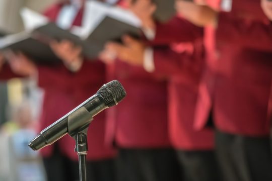 Mikrofon vor einem Männerchor